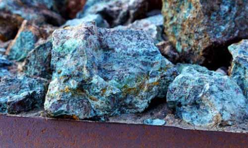 Chunks of copper ore mineral rocks in an iron barrel