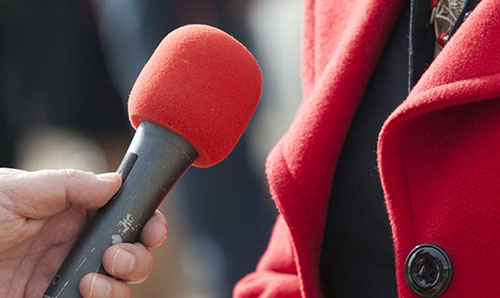 A reporter holding a microphone in front of an interviewee