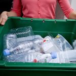 A photo of someone holding a small plastic recycling bin