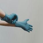 A person putting on blue medical gloves.
