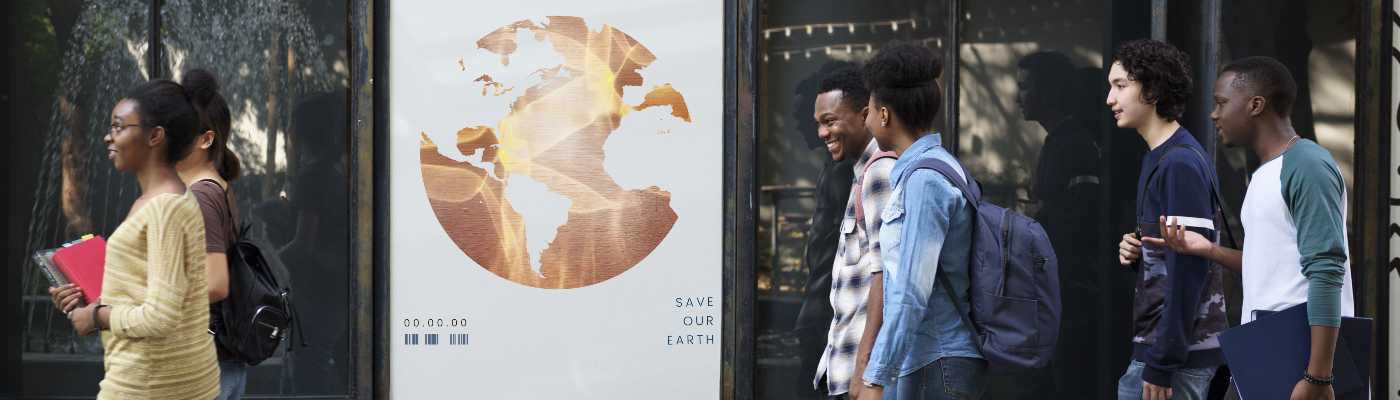 A group of students wearing backpacks and chatting walk past a billboard